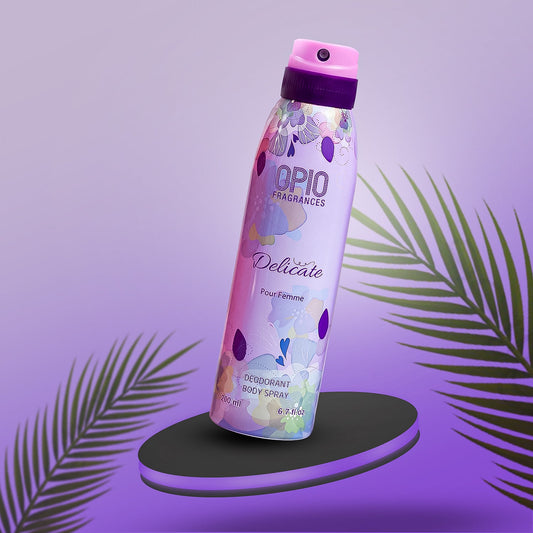 A bottle of OPIO Delicate body spray with a floral design, placed on a purple platform with a palm leaf in the background.