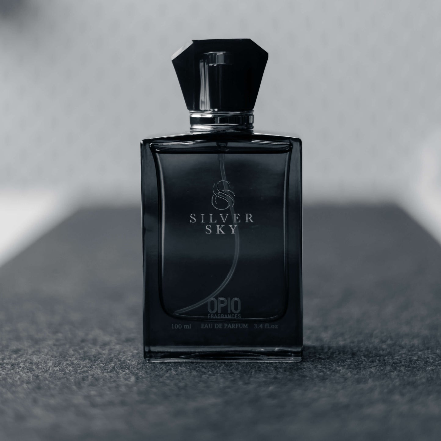 A black perfume bottle with a clear liquid, branded Silver Sky by Opio.