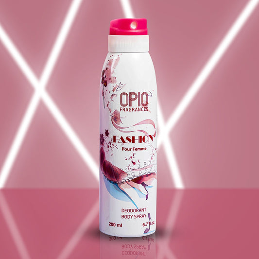 A bottle of OPIO Fashion body spray for women, with a pink cap and a floral design on the label, set against a pink background with light trails.