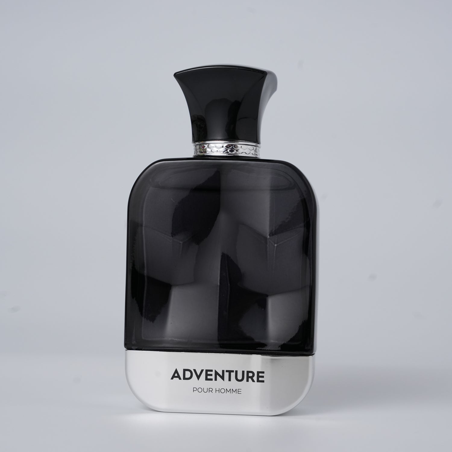 A sleek black perfume bottle labeled "ADVENTURE POUR HOMME" with a silver base and ornate cap, set against a light gray background.