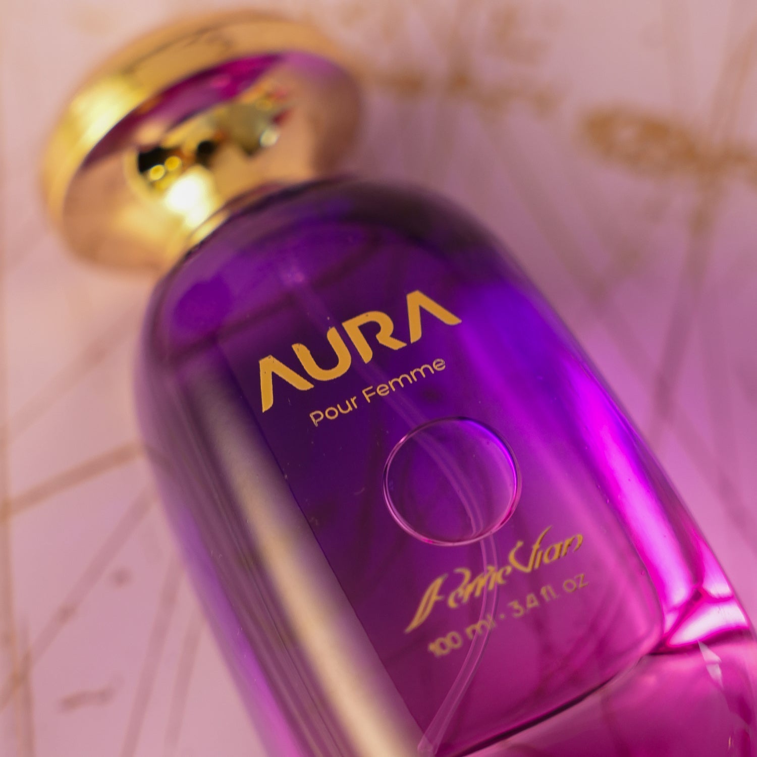 Perfume bottle labeled 'AURA' with a purple gradient and gold cap.