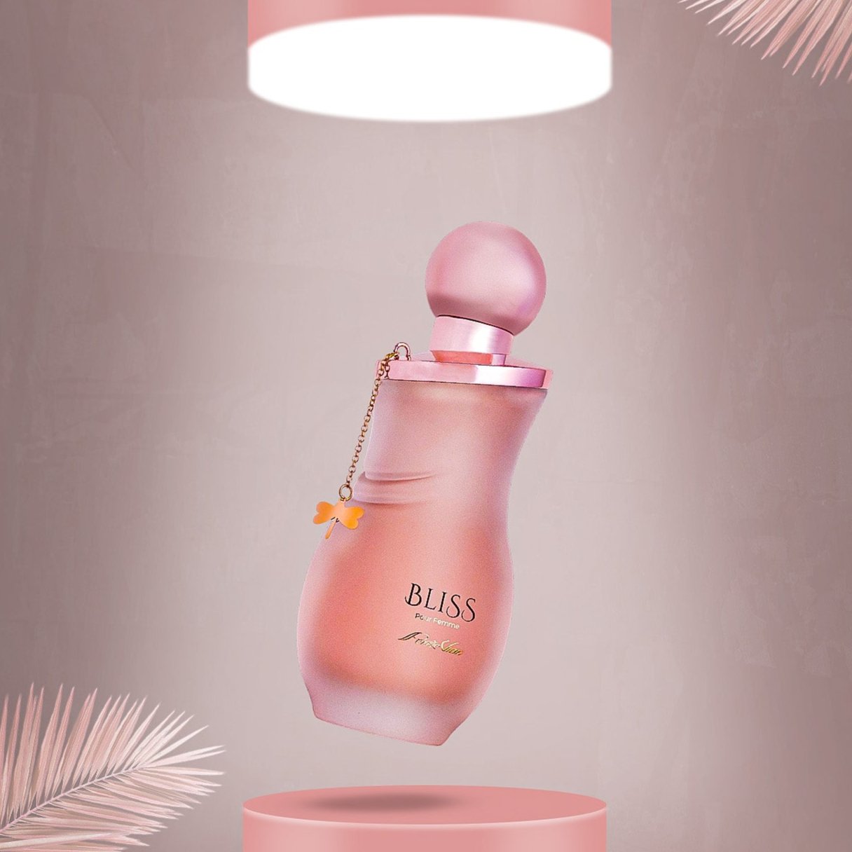 A bottle of 'Bliss' perfume for women, with a pink label and cap, displayed against a pink and green background with a decorative palm leaf.