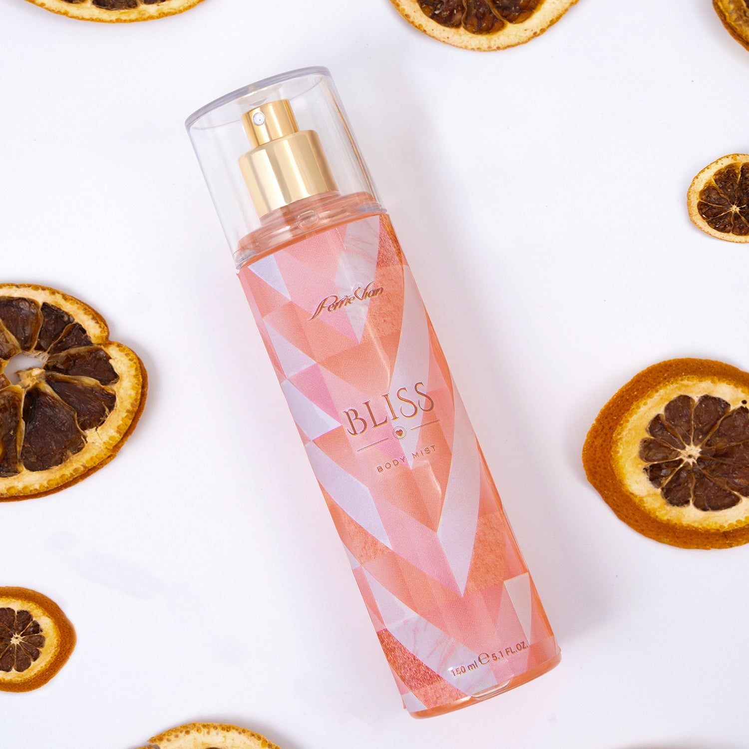 A bottle of 'Bliss' body mist for women, with a clear liquid visible inside the bottle. The bottle is placed on a surface with several sliced oranges and whole oranges in the background.