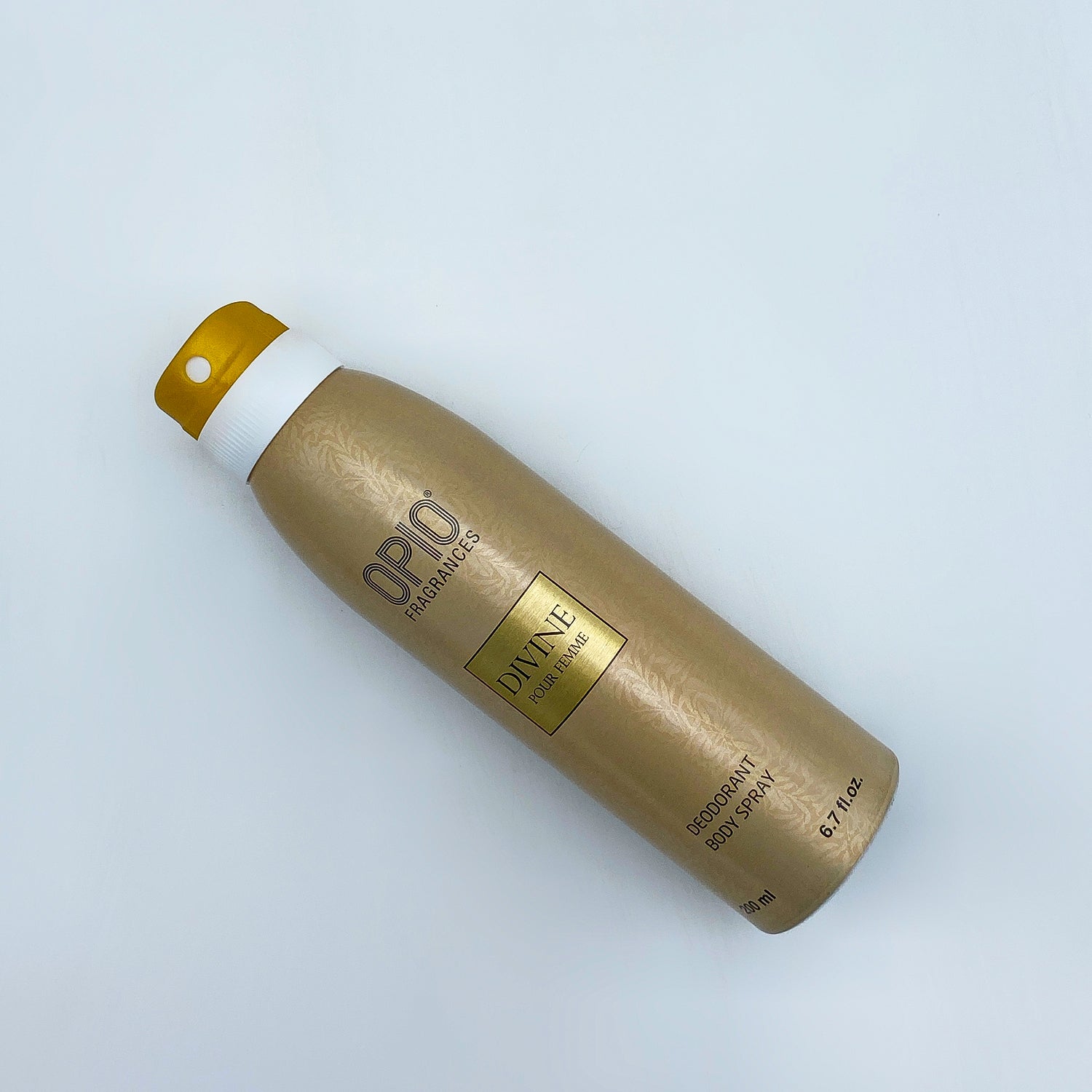 Deodorant spray bottle with gold and white design on a light gray background
