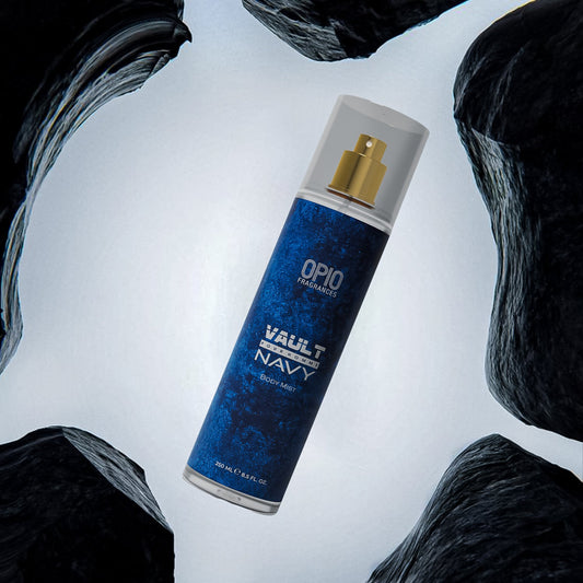A spray bottle of OPIO Vault Navy body mist, displayed in a cool, cavern-like setting with dark rocks around.