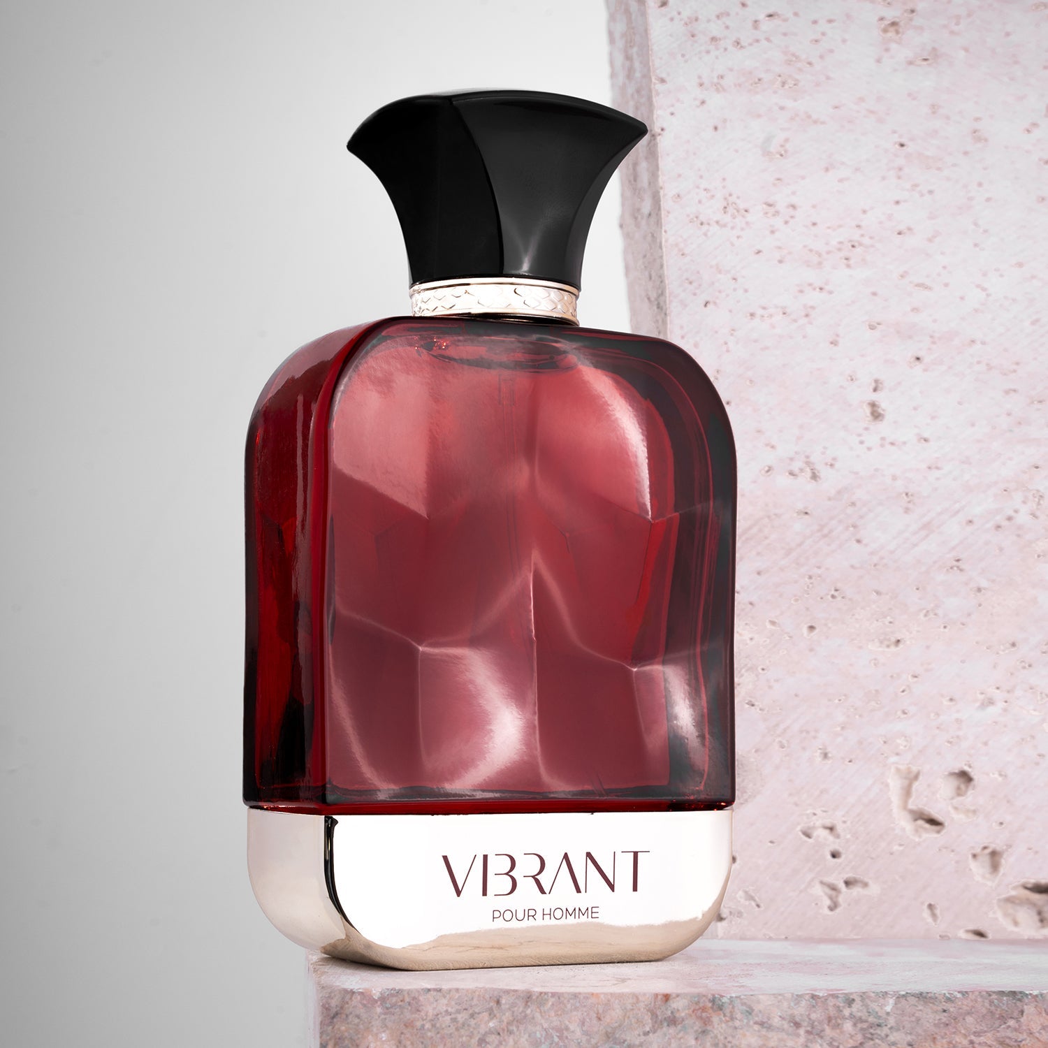 A stylish red and silver perfume bottle labeled 'VIBRANT POUR HOMME' with a black, sculpted cap.